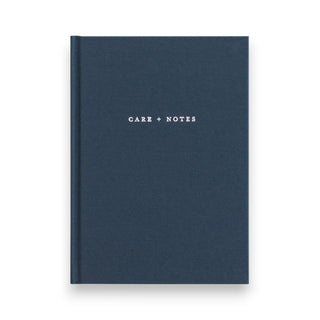 Navy blue linen covered notebook with 'Care + Notes' text on a white background