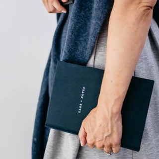 Person holding a navy notebook with 'Care & Notes' branding against a neutral background