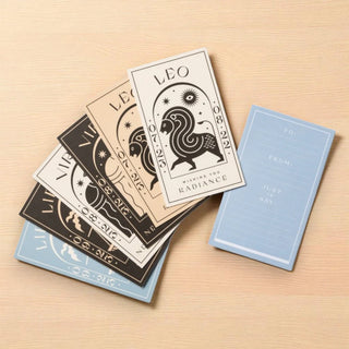 Set of gift cards with zodiac designs on a wooden surface