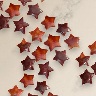 Star-shaped red carnelian crystals on a light marble background