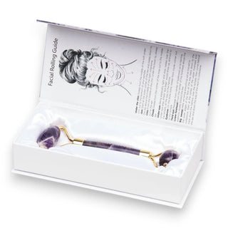 Facial roller made with amethyst stone in a box with instructions on a white background