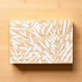 Wooden cutting board with white abstract pattern on a wooden surface