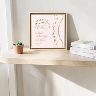 Framed artwork with motivational quote on a wooden surface with books and a plant.