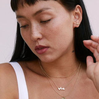 Woman wearing necklaces with a plain background