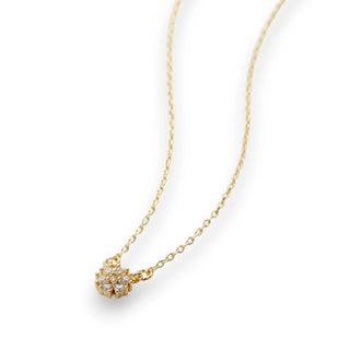 Gold necklace with a delicate gemed flower pendant on a white background