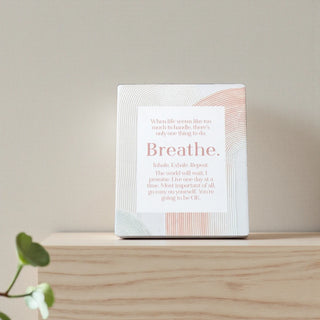 White ceramic plaque with motivational text on a wooden surface with a light background