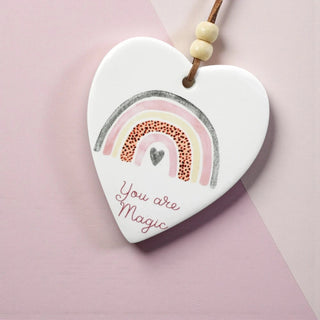 Heart-shaped ceramic ornament with rainbow design and 'You are Magic' text on a pink background