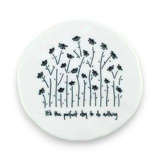 Round white coaster with black floral design and text on a white background