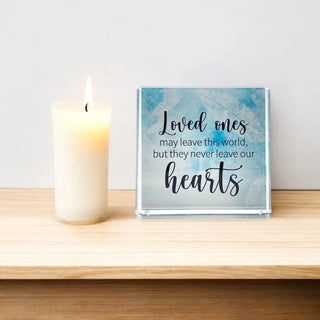 Decorative plaque with inspirational quote: Loved ones may leave this world but never leave our hearts, on a light blue background