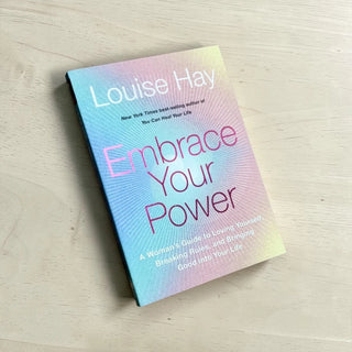 Book titled 'Embrace Your Power' by Louise Hay on a light wooden surface