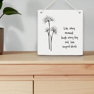 Decorative wall hanging with floral design and motivational quote on a wooden surface.