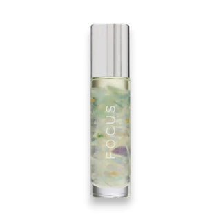 Roll-on bottle of essential oils with fluorite chips and 24k gold flakes in a clear bottle with a decorative cap on a white background