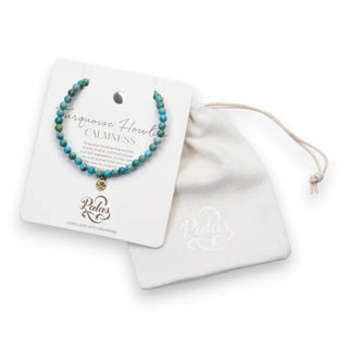 Turquoise beaded bracelet on a display card with a white drawstring bag on a white background