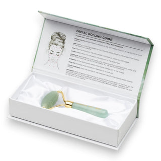 Gua Sha tool in a white box with a facial rolling guide on a white background