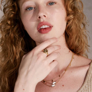 Woman wearing gold jewelry with a neutral background