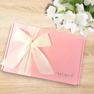 Pink gift box with a bow and flowers on a wooden surface