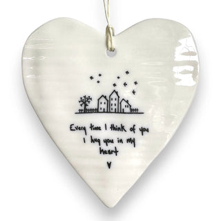 Heart-shaped ceramic ornament with a house illustration and text on a white background