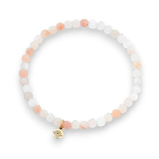 Bracelet with peach aventurine beads and a gold lotus charm on a white background