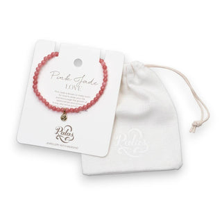 Pink jade beaded bracelet on a white card with 'Palas' branding, next to a white drawstring bag.