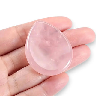 Pink teardrop-shaped rose quartz crystal held in a hand against a white background
