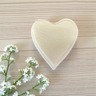 Underside of the Heart-shaped coaster with a felt backing on a wooden surface with white flowers