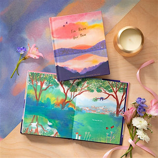 Colorful grief support book with nature-themed designs on a wooden surface with flowers and a candle.