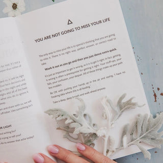 Open book with text and a hand holding a leaf