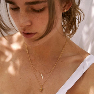 Close-up of a person wearing gold necklaces with a neutral background