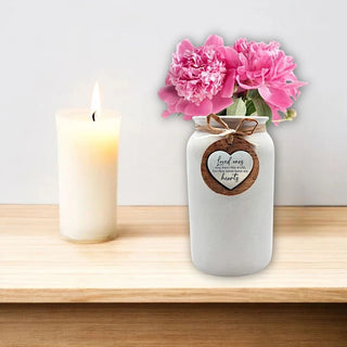 White ceramic Memorial Vase with an inscription on a heart shaped metal tag saying: Loved ones may leave this world, but they never leave our hearts.