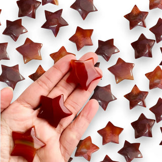 Star-shaped Carnelian mini crystals held in a hand with a white background