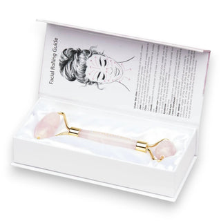 Facial roller with pink rose quartz stones in a white box with instructions on a white background