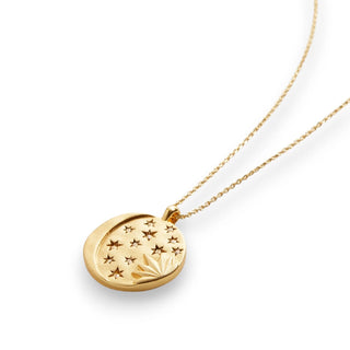 Gold necklace with a circular pendant featuring stars and a moon on a white background