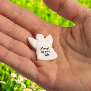 Small white andel-shaped object with 'Always by your side' text held in a hand against a blurred green background.