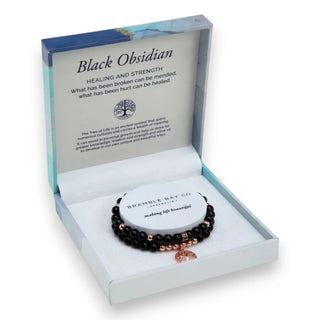 Black obsidian bracelet duo in a decorative box with text about its properties.