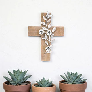 Wooden cross with floral and butterfly design on a white wall, accompanied by three potted succulents.