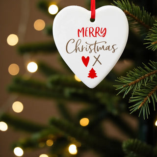Heart-shaped Christmas ornament with 'Merry Christmas' text and decorations on a tree.